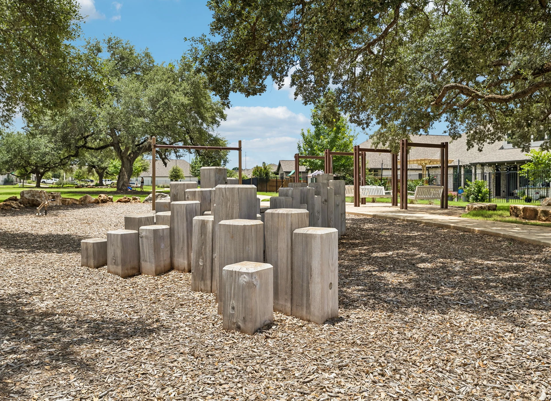 Playground with wooden climbing structures and trees.