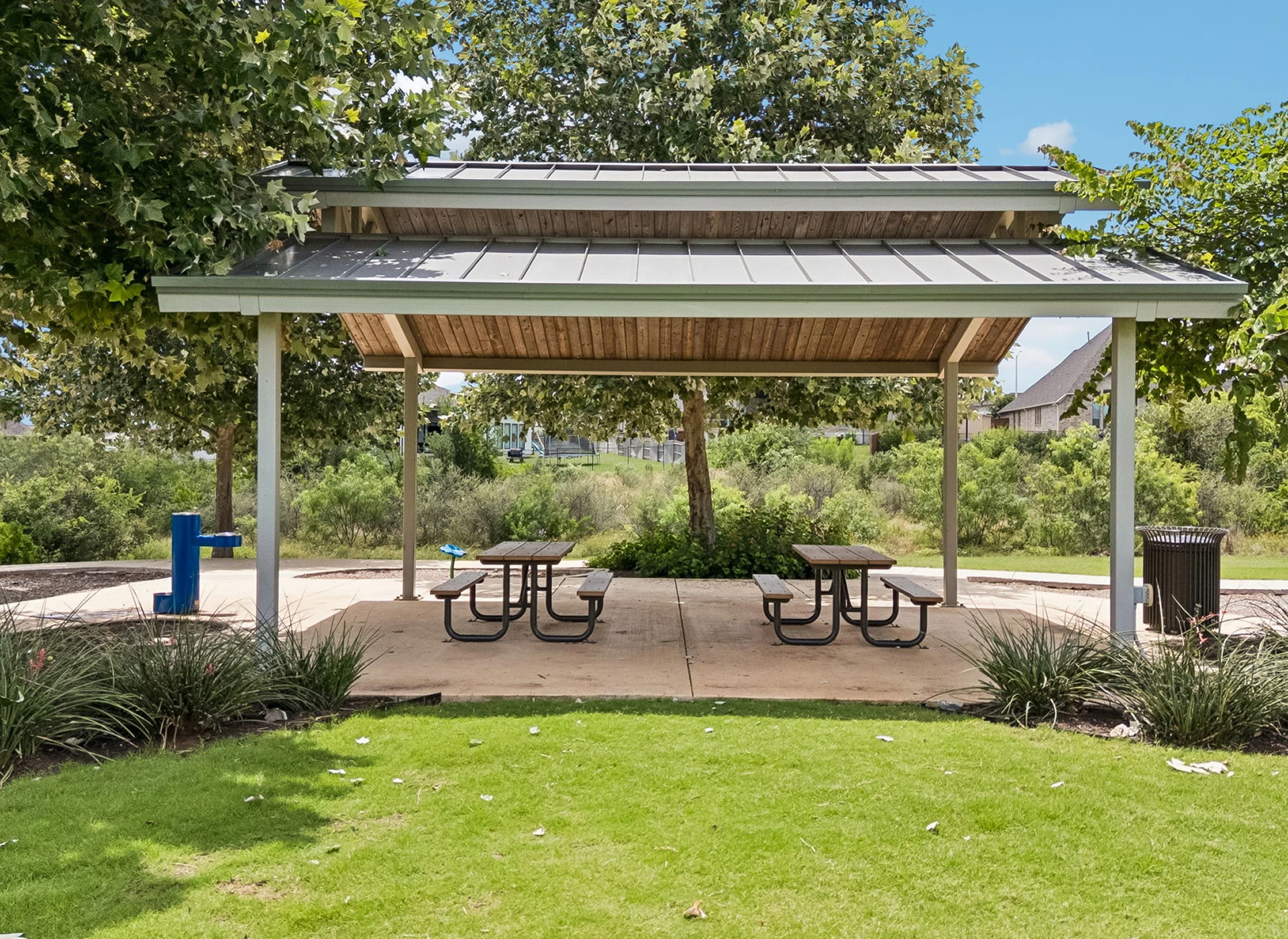 Park pavilion with picnic tables and trees.