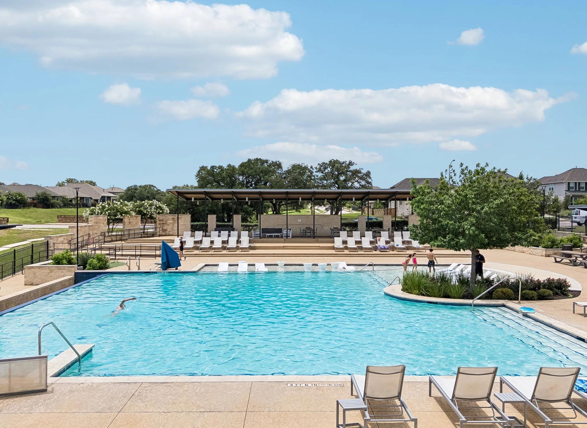 Outdoor swimming pool with lounge chairs, trees.